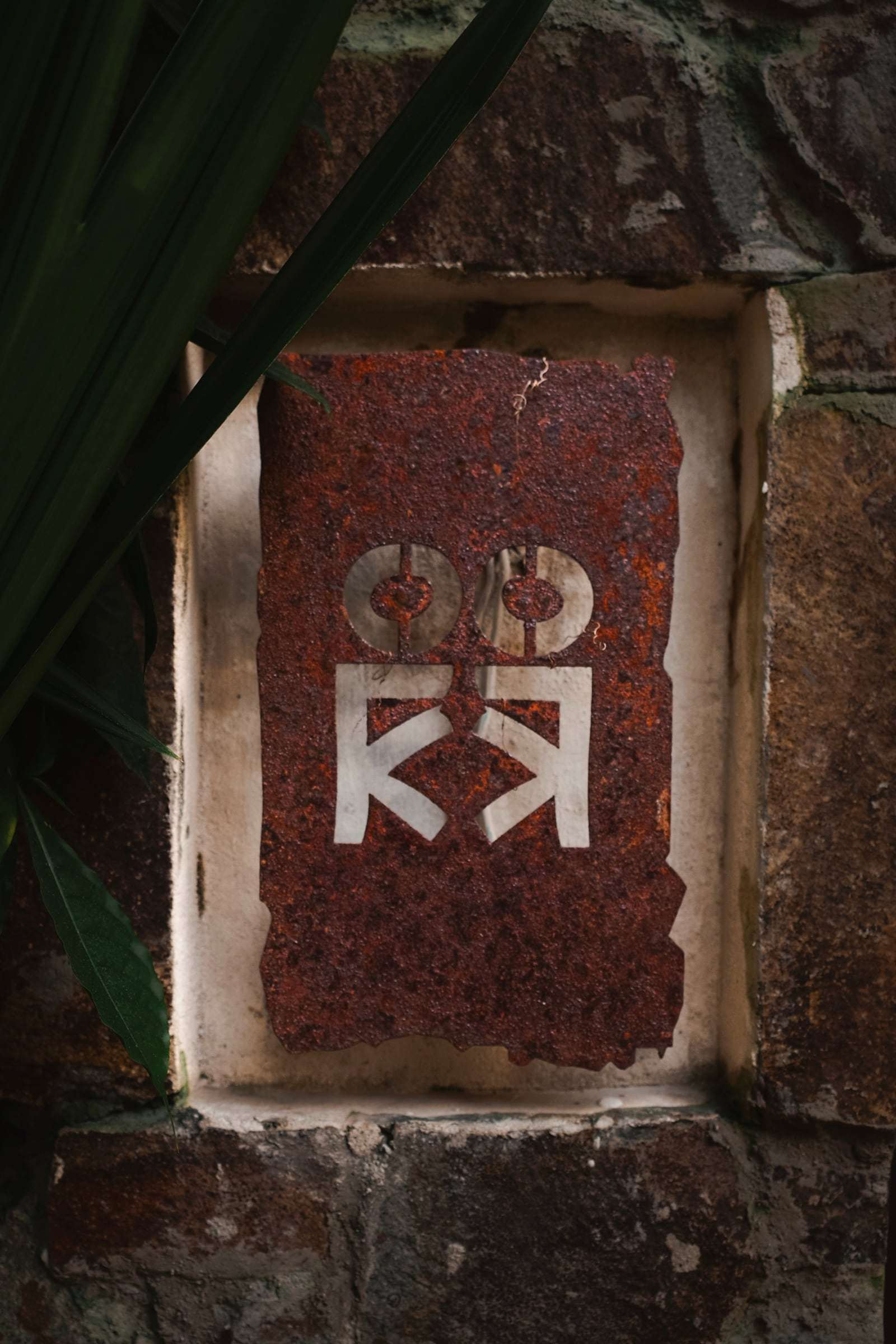 Rusted-steel plaque with the cut-out Conga emblem, set into a stone wall