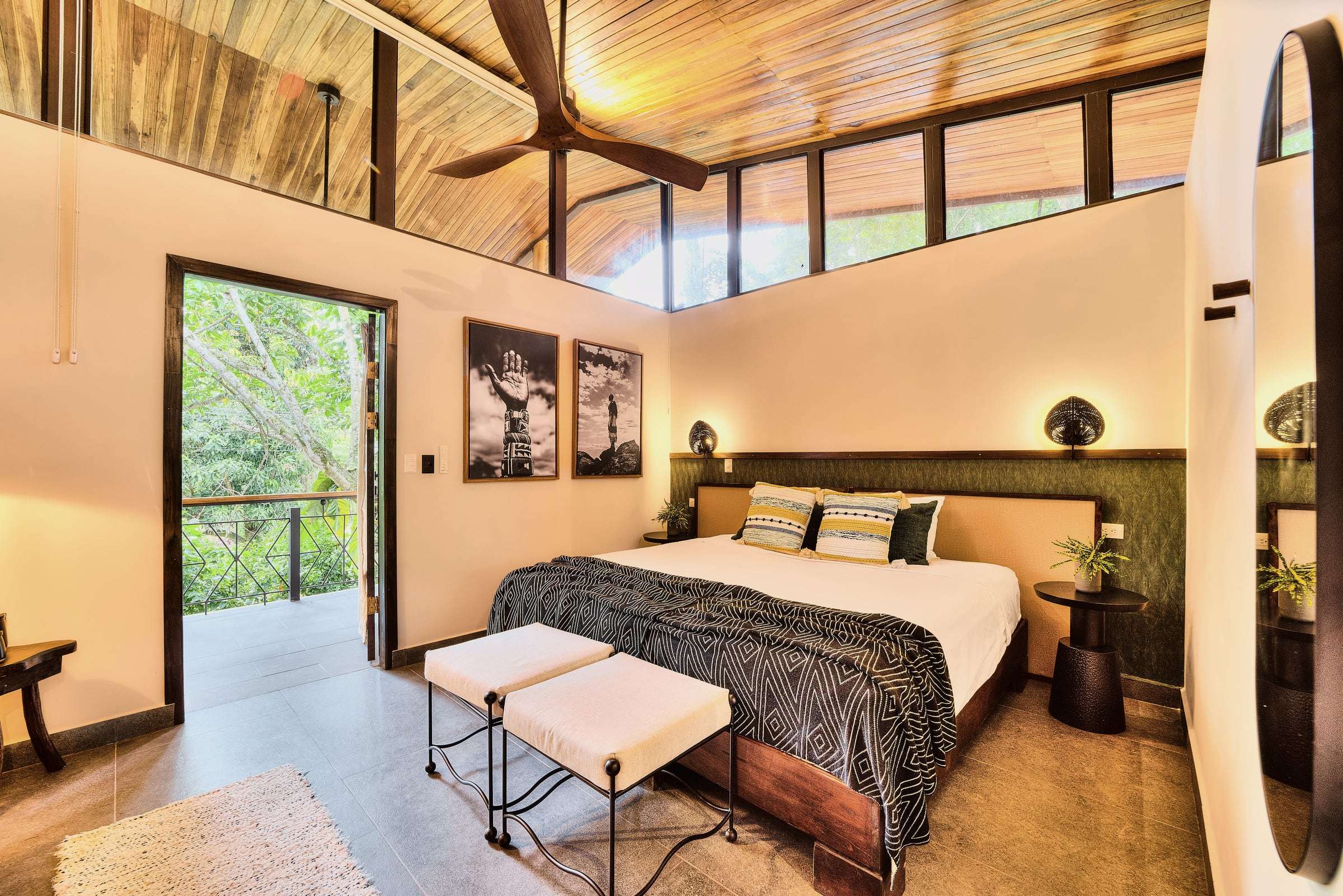 Jungle View Suite: king bed with benches, black-and-white prints, clerestory windows and a door open to the treetops