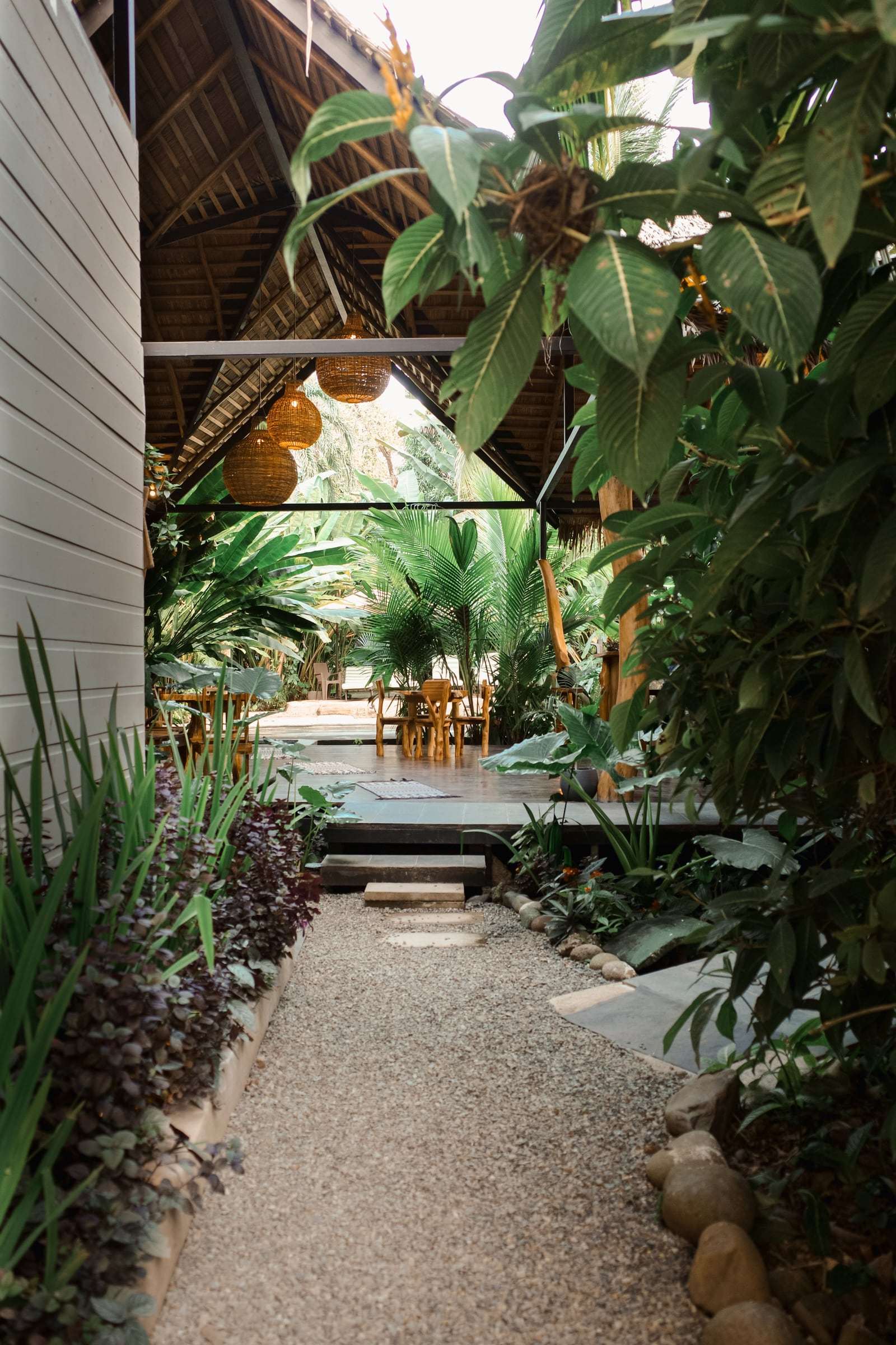 Gravel path between the white wing and the garden, leading to the thatched rancho with rattan lamps