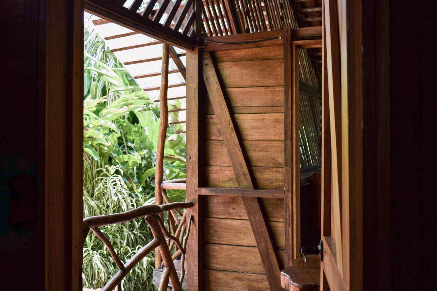Garden Home: wooden door opening past a branch railing onto banana leaves and jungle