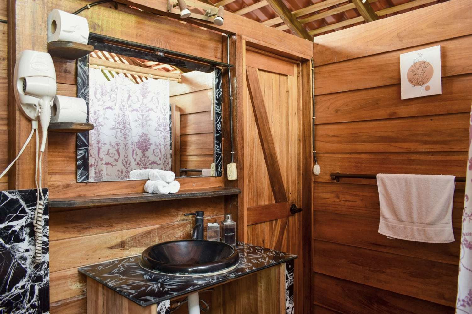 Garden Home bathroom vanity: dark vessel sink on a marble-effect counter, mirror and warm wood panelling