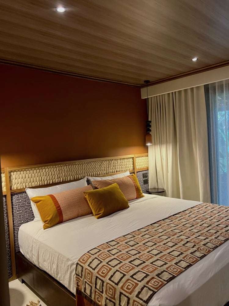 Grand Oasis Suite: king bed with a woven headboard, terracotta wall, mustard cushions and a geometric runner