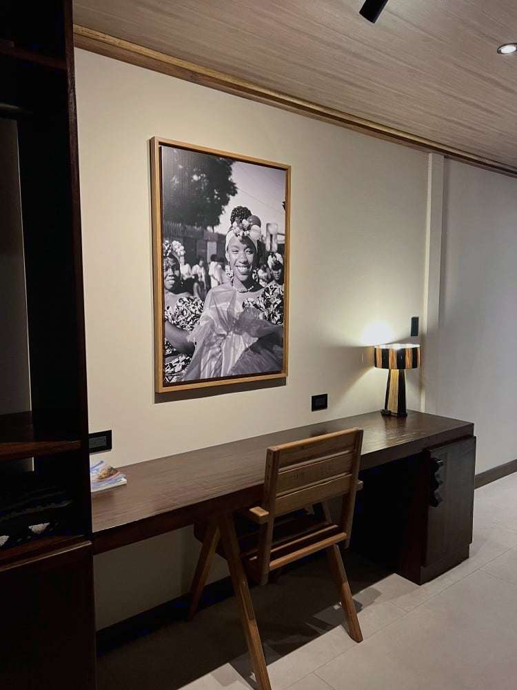 Grand Oasis Suite: long wooden desk and chair beneath a large black-and-white portrait of a smiling woman