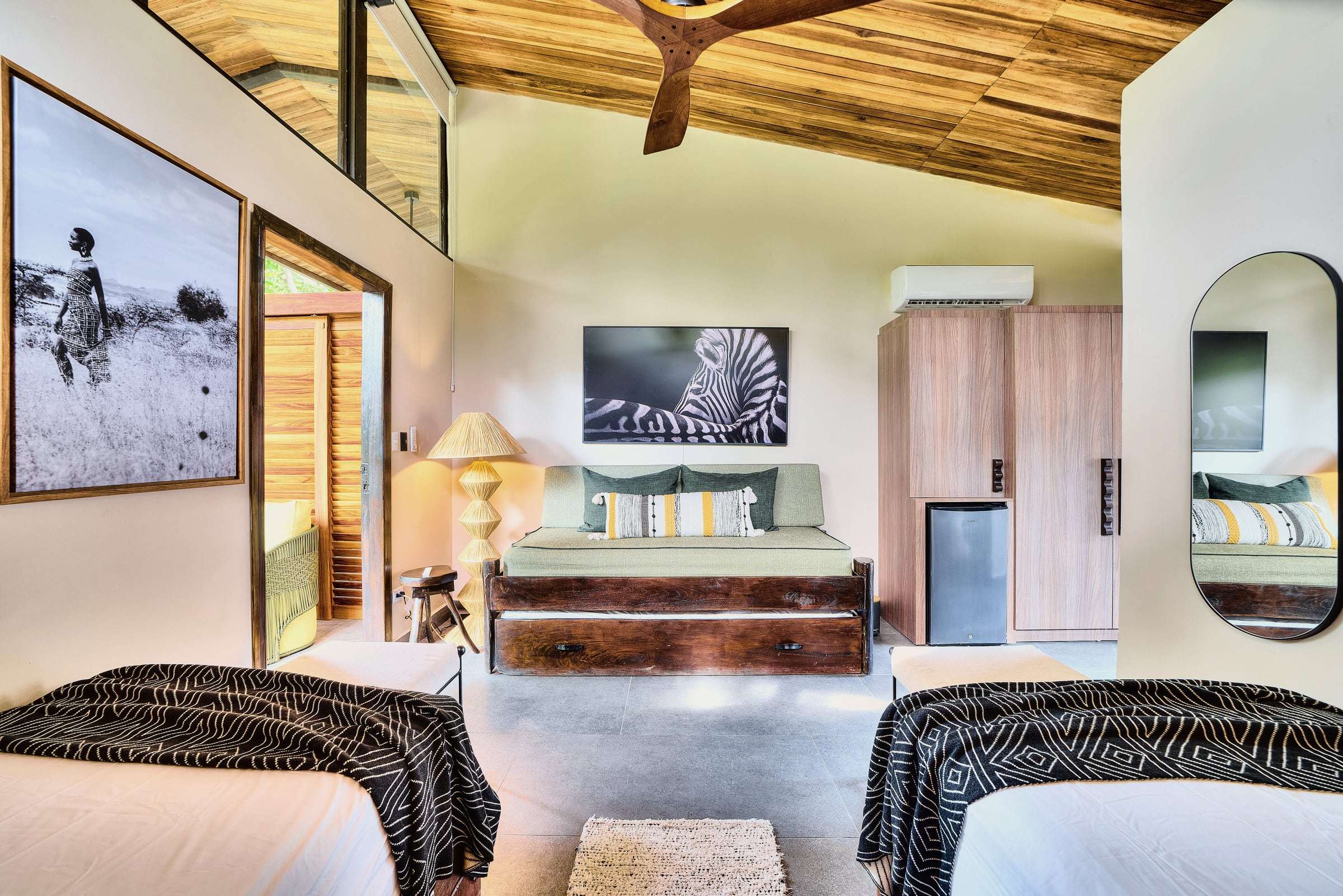 Jungle View Suite: twin beds facing a green daybed, raffia floor lamp, zebra print and a wardrobe with minifridge