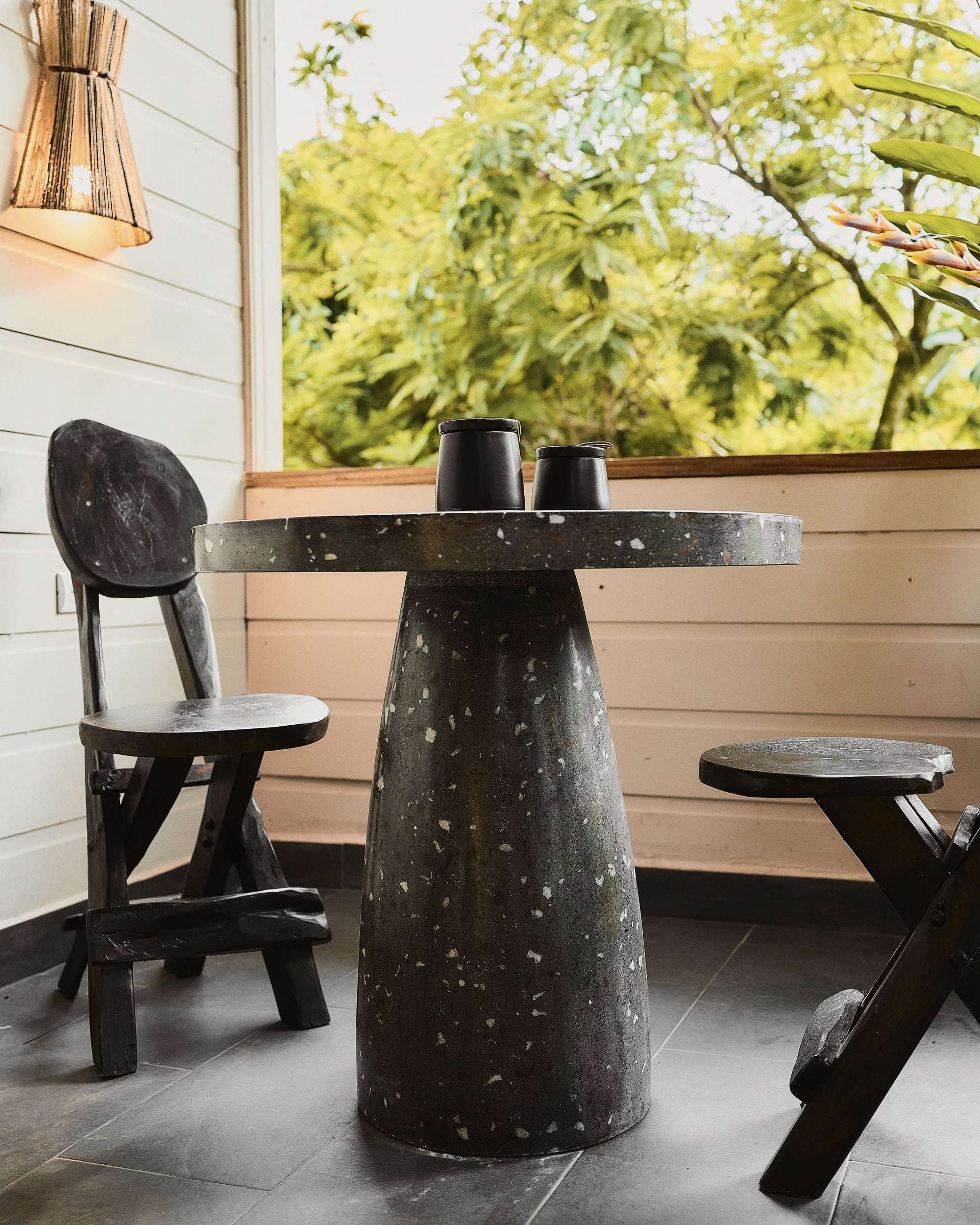 Jungle View Suite terrace: terrazzo bistro table with two mugs and carved wooden chairs, treetops beyond