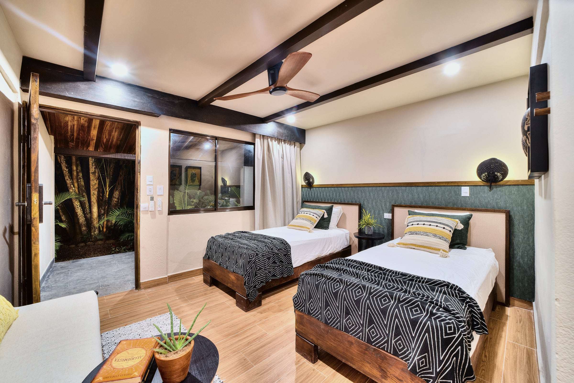 Superior Garden Room with twin beds, geometric throws, a green headboard wall and a door open to the garden at night