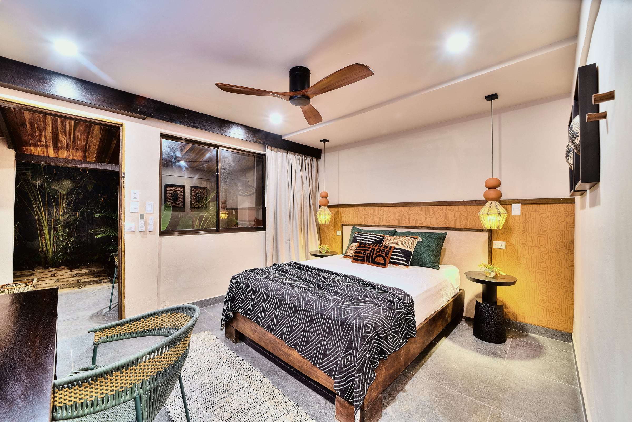 Superior Garden Room: queen bed with a geometric throw, ochre headboard wall, beaded pendants and a door to a patio